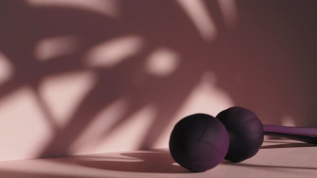 Purple kegel balls in a soft pink neutral background / Geisha balls pelvic floor healthcare video / Ben wa balls feminine concept / Vaginal balls sex toy concept. 