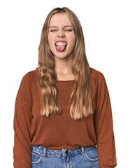 Studio portrait of a blonde Caucasian woman funny and friendly sticking out tongue.