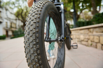 Naklejka premium Selective focus on tubeless tire of an electric motor bike, mountain bike. Shallow tread of a bicycle tubeless tire. Cropped view of electric bike bicycle wheel. Copy ad space