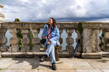 Fototapeta premium portrait of happy middle aged traveler woman on vacation sitting in an outdoor terrace in front of lake Maggiore