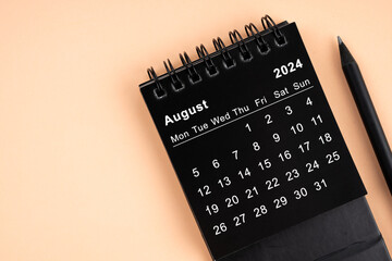 Augustl 2024 Black spiral desktop calendar and wooden pencil.