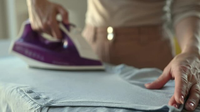 Girl hand using iron with steam mode for wrinkled clothes. Woman with hot electric tool smoothing textile