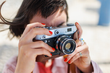 Beautiful woman takes photographs outdoors with an analog camera.
