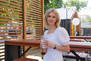 Woman in white dress outdoor, relaxing at summer street festival