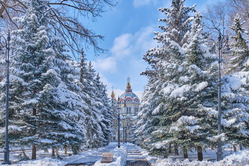 Snowy alley in Panfilov park, Almaty, Kazakhstan. Russian Orthodox Ascension wood Cathedral