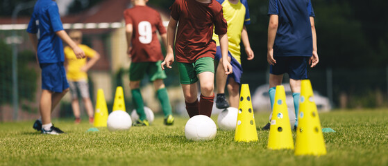 Slalom practice for football players. Youth in sports training. Player kicking ball during a soccer training drill. Summer sports practice camp for school kids