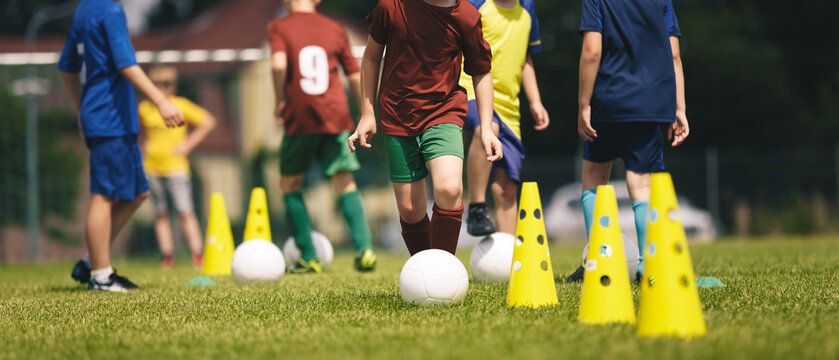 Slalom practice for football players. Youth in sports training. Player kicking ball during a soccer training drill. Summer sports practice camp for school kids