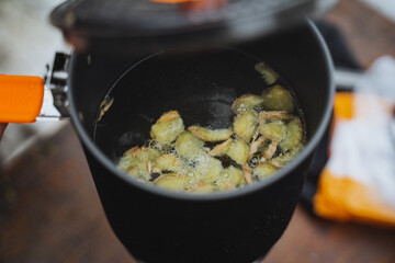 Pieces of ginger are boiled in boiling water in a saucepan, the lid of the cauldron is ajar, making a hot drink, ginger warming tea.