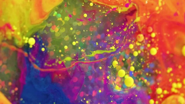 Vertical video. Colorful flow background. Paint blend. Spill art. Fantasy bright yellow red blue pink liquid ink abstract splash mix rotating in water with shiny sequins circles.