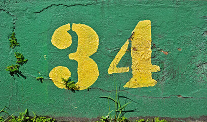 Number 34 painted in yellow on a green wall