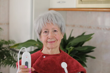 Senior woman with neck pain using electric heated pad 