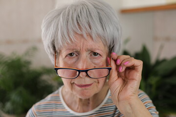 Senior woman squinting and putting her eyeglasses down 