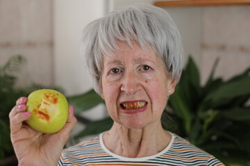 Senior woman with bloody gums after bitting an apple 