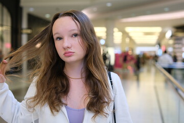 Young beautiful woman walking along the street doing shopping, stylish girl looking at clothes shop window.