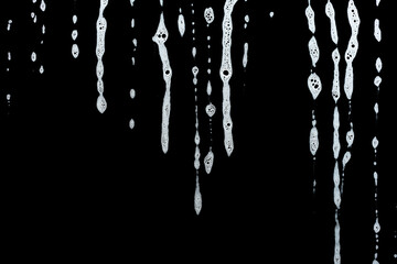 soap foam dripping from window glass, white foam on black background