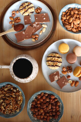 Cup of tea or coffee, cookies, macaroons, chocolate, various nuts and cocoa powder on wooden table. Top view.