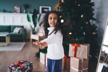 Happy beautiful girl standing in cozy home with Christmas decorations and gift boxes