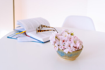 still life vase flowers, an open book, reading glasses, on white table