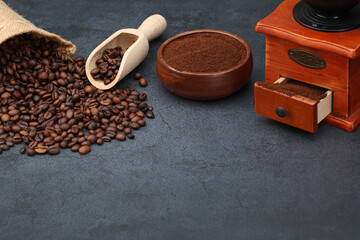 Kaffeepulver mit gerösteten Kaffeebohnen und Kaffeemühle auf dunklem Hintergrund mit Platz für...