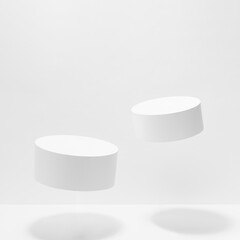Set of two round tilt white pedestals for cosmetic products mockup, fly in hard light, shadow on white background. Stage for presentation skin care products, gifts, goods, advertising in summer style. - 779727371