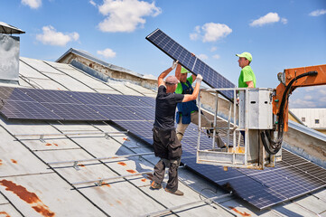 Workers lifting up photovoltaic solar panel on metal rooftop of house with assistance of crane...