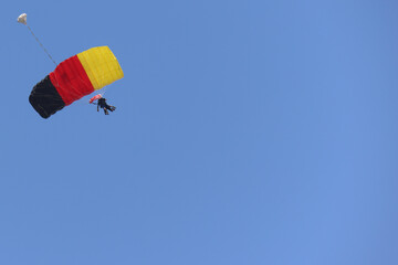 Tandem skydiving (parachuting), clear blue sky day. Parachute decorated in the Germany flag colors. Copy space.