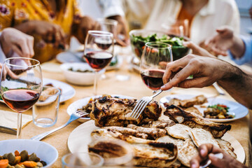 Happy family having bbq dinner party in restaurant rooftop - Group of people eating meat and drinking red wine glasses together - Food and beverage concept
