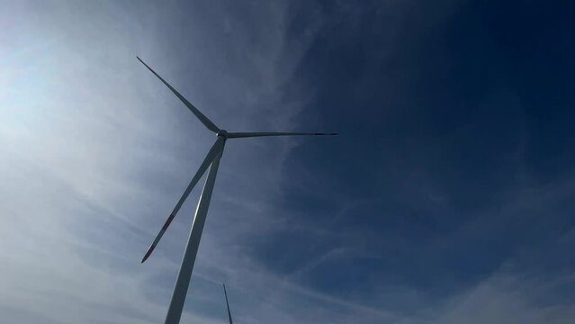 Wind turbine produce energy, modern power plant, alternative energy sources. Wind turbine rotating with blue sky on background.