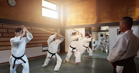 Aikido, group and class with sensei, weapon training and wooden sword for self defence exercise. Dojo, student or athlete in Japanese studio gym with fight challenge, black belt practice and fitness
