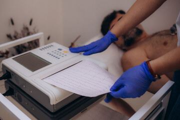 apparatus or device the unit of measurement of the electrocardiogram in a doctor's office. Male patient having ECG electrocardiogram in hospital. selective focus