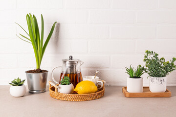 Beautiful kitchen background with glass teapot of fragrant tea, cup, lemon on wicker tray. Front...