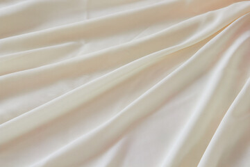 background of beige fabric in waves, Soft pastel beige cream color, shiny satin silk swirl wave...