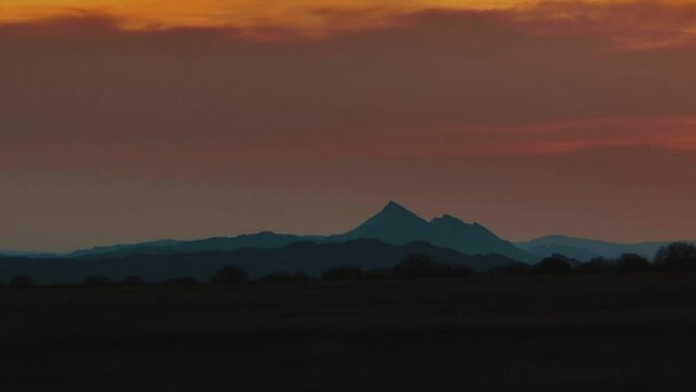 Drone shot of rocky peaks of desert mountains at the sunset .