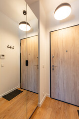 Stylish hallway interior with wooden doors and reflective mirror