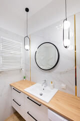 Modern bathroom interior with round mirror and marble walls