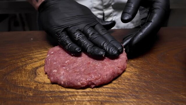 A man prepares a cutlet from raw minced meat