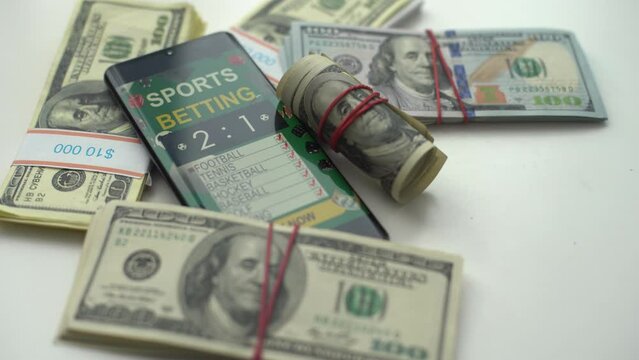 Smartphone with gambling mobile application and soccer ball with money close-up. Sport and betting concept