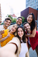 Young group of people having fun enjoying free time together taking selfie portrait at city street. Millennial student friends laughing outdoors. Youth community concept.