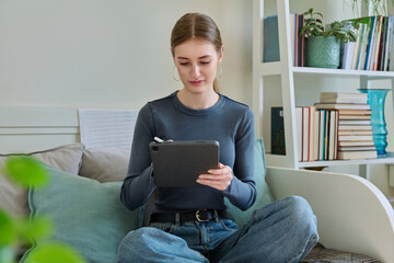 Young female teenager with digital tablet, stylus drawing illustrating sitting at home