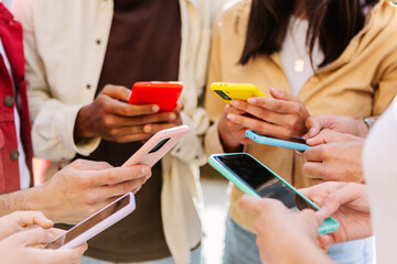 Closeup view of young group of people hands using mobile phone outdoors. Millennial people connected online browsing internet on smartphone device. - obrazy, fototapety, plakaty