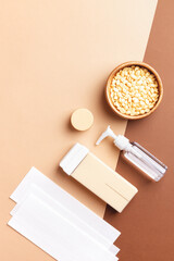 Vertical composition with hair removal, depilation tools on beige-brown background. Body care,...