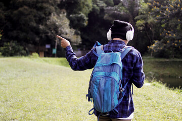 Bewildered young Asian man in a casual outfit studies his phone map. He points his finger to the...