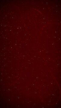 Vertical Christmas Glitter Swirl Snow 4K Loop features a dark red atmosphere with subtle swirls and particles animating on and off the screen in a vertical ratio loop. 