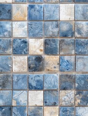 A grid of distressed, cracked tiles in shades of blue and beige, creating a visually striking abstract pattern with a vintage, weathered aesthetic.