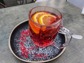 Close-up of a hot tea mug with grenadine and fruits on a table in a cafe