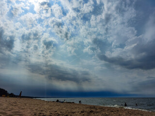 Seascape of the sea with yellow sand on the shore and very dark blue and white contrasting clouds above
