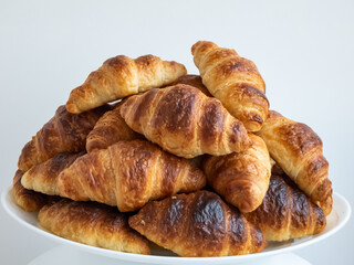 Close-up of a pile of fresh baked french croissants on white plate on white background
