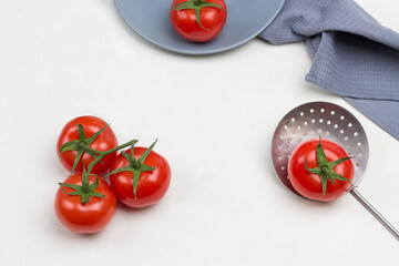 Tomatoes on green branch. Tomato and allspice on gray plate. Tomato with green tail on skimmer