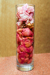 A tall wall vessel filled with rose petals.