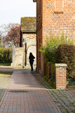 Eine Spazierg&auml;ngerin in der Pomeranzengasse Richtung Ritterstra&szlig;e M&uuml;nchhausenhof in Rinteln an einem sonnigen Tag 